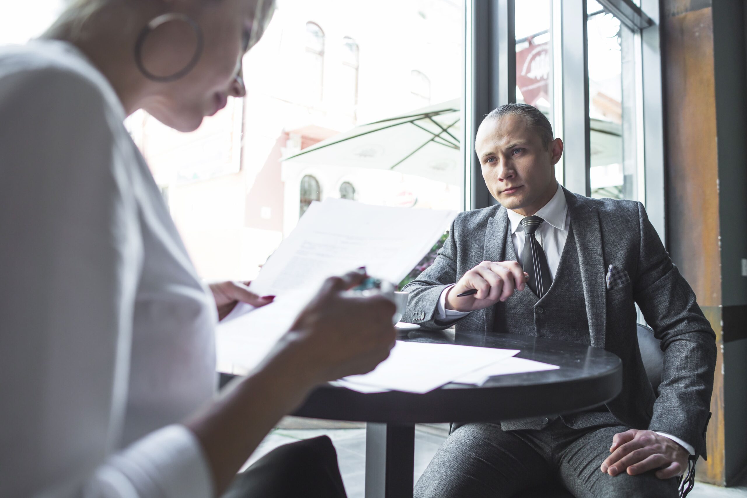 businesswoman-looking-his-colleague-examining-document-caf